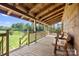 Covered porch with wood benches and a view to a grassy lawn and pond at 11227 Cool Springs Rd, Cleveland, NC 27013