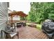 Wooden deck with a covered seating area, fire pit, and grill in the landscaped backyard at 120 Tranquil Ct, Locust, NC 28097
