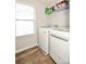 Bright laundry room with wood-look flooring, white appliances, window, and shelf at 120 Tranquil Ct, Locust, NC 28097