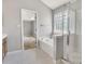 Bright bathroom featuring a glass shower, tub, and a window letting in natural light at 1458 Bedlington Nw Dr, Charlotte, NC 28269