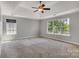 Bright and airy bedroom featuring neutral walls, plush carpeting, a ceiling fan, and large windows for natural light at 1458 Bedlington Nw Dr, Charlotte, NC 28269