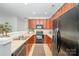 Functional kitchen with wood cabinets and black appliances offers efficient space utilization at 15554 Stronvar House Ln, Charlotte, NC 28277