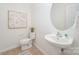 Compact powder room features a pedestal sink, toilet, artwork, and neutral walls at 15554 Stronvar House Ln, Charlotte, NC 28277