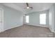 A light and airy bedroom with a ceiling fan, two windows, and neutral carpeting at 15623 Sir Charles Pl, Charlotte, NC 28277