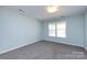 This cozy bedroom features soft blue walls, plush gray carpet, and a bright window at 15623 Sir Charles Pl, Charlotte, NC 28277