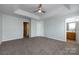 Bedroom featuring neutral walls, a tray ceiling with fan, and doorway to bath at 15623 Sir Charles Pl, Charlotte, NC 28277