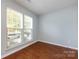A light-filled bedroom featuring hardwood floors and large windows offering a pleasant outdoor view at 15623 Sir Charles Pl, Charlotte, NC 28277