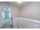 Upstairs hallway with neutral walls and carpeting leading to a bedroom with a ceiling fan at 15623 Sir Charles Pl, Charlotte, NC 28277
