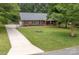 A well-manicured front yard and long driveway lead up to this charming brick home with black shutters at 1610 Ford St, Charlotte, NC 28216