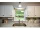 Kitchen sink under window, featuring stainless steel appliances and white cabinetry at 1610 Ford St, Charlotte, NC 28216