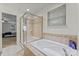 Bathroom featuring large tub, glass enclosed shower, and tiled walls with window letting in natural light at 16615 Crimson Sargent Dr, Charlotte, NC 28213
