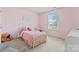 Cozy bedroom with pink walls, featuring a twin bed with soft bedding and a bright window at 16615 Crimson Sargent Dr, Charlotte, NC 28213