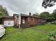 Brick home's backyard features a covered porch, manicured lawn, and a blend of natural beauty, perfect for relaxing at 2009 Hickory Grove Rd, Gastonia, NC 28056