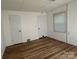 A sunlit empty room featuring wood-look flooring, white walls, a window, and two doors at 2009 Hickory Grove Rd, Gastonia, NC 28056