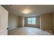 A vacant bedroom with neutral walls, one window, and plastic on the carpet awaiting personalization at 2046 Sabra St # Cwo0006, Gastonia, NC 28054