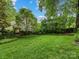 Lush backyard with mature trees and a charming garden gate, offers tranquility and privacy at 2432 Hassell Pl, Charlotte, NC 28209