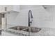 Close up on kitchen sink featuring modern faucet, granite countertops, white backsplash and white cabinets at 2511 Linwood Rd, Gastonia, NC 28052