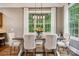 Dining room with a wooden table, upholstered chairs, modern light fixture and a large window with wooded backyard view at 309 Palm Cove Way, York, SC 29745