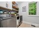 Well-equipped laundry room with modern appliances, cabinet storage, and floating shelves and a bright window at 309 Palm Cove Way, York, SC 29745