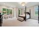 Main bedroom featuring a four-poster bed, neutral carpeting, large windows, and a seating area at 309 Palm Cove Way, York, SC 29745