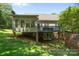 Backyard view with a deck, climbing wall, brick foundation, and lush lawn at 327 Wilby Dr, Charlotte, NC 28270