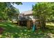 Lush backyard featuring a deck, covered patio with a slide and swing set, and a grassy lawn at 327 Wilby Dr, Charlotte, NC 28270