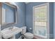 Cozy half bathroom featuring a pedestal sink, a window, and blue painted walls at 327 Wilby Dr, Charlotte, NC 28270