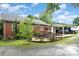 A brick home shows a paved backyard patio, seating, and partial shelter for parked vehicles at 3700 Nevin Rd, Charlotte, NC 28269