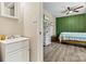 View from a bathroom into a green accent wall bedroom with wood-look flooring, a bed with a floral quilt at 413 Picadilly Ln, Troutman, NC 28166
