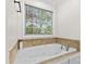Close up on a soaking tub with tile surround and a window with privacy blinds at 4336 Hunter Rhyne Rd # 9, Lincolnton, NC 28092