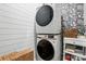 Convenient laundry room with modern stacked washer and dryer, complemented by stylish wallpaper and wood detail at 4842 Durneigh Dr, Kannapolis, NC 28081