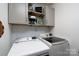 Functional laundry room with white subway tile backsplash, washer, and dryer hookups and decor shelves at 503 New Castle Ne Ct, Concord, NC 28025