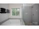 This bathroom includes a modern shower and a separate soaking tub with a large window view at 6009 Swanston Dr, Charlotte, NC 28269