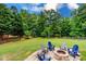 Backyard features a stone fire pit and Adirondack chairs on a lush green lawn at 6202 Pumpernickel Ln, Wesley Chapel, NC 28110