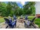 Backyard with a circular stone fire pit surrounded by Adirondack chairs on a stone patio at 6202 Pumpernickel Ln, Wesley Chapel, NC 28110