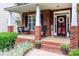 Charming brick front porch, complete with a swing and vibrant plants, exudes southern charm at 6202 Pumpernickel Ln, Wesley Chapel, NC 28110