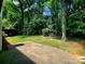 A patio leads to a green backyard, lined with lush, mature trees at 7228 Rollingridge Dr, Charlotte, NC 28211