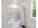 Bathroom with a white tub shower combo and a window to the outside, providing natural light at 7308 Rothmore St, Charlotte, NC 28215