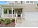 Inviting covered porch with white railing and pillars leads to the front door and attached two-car garage at 7308 Rothmore St, Charlotte, NC 28215