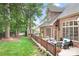 A spacious brick home features a backyard with a wooden deck, lush green lawn, and wooded surroundings at 7738 Burning Ridge Dr, Stanley, NC 28164