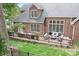 A spacious brick home features a backyard with a wooden deck, lush green lawn, and wooded surroundings at 7738 Burning Ridge Dr, Stanley, NC 28164