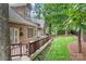 A spacious brick home features a backyard with a wooden deck, lush green lawn, and wooded surroundings at 7738 Burning Ridge Dr, Stanley, NC 28164