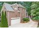 The brick home features an attached garage, driveway, manicured lawn, mature trees and well-maintained landscaping at 7738 Burning Ridge Dr, Stanley, NC 28164
