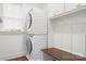 Efficient laundry room with stacked washer and dryer, storage cabinets, and bench at 7738 Burning Ridge Dr, Stanley, NC 28164