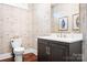 Chic powder room with decorative wallpaper, vanity with dark cabinets, and modern fixtures at 7738 Burning Ridge Dr, Stanley, NC 28164