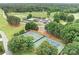 Aerial view showcasing tennis courts alongside a clubhouse, pool, golf course, and ample parking at 7738 Burning Ridge Dr, Stanley, NC 28164