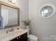 Stylish half-bathroom with a marble countertop, round window, and dark wood cabinetry at 8605 Tamarron Dr, Charlotte, NC 28277