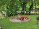 Backyard fire pit area with red Adirondack chairs, perfect for outdoor entertaining in a lush green setting at 906 Eastwood Dr, Rock Hill, SC 29730