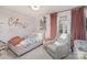 Cozy bedroom with pink walls, cute décor, a comfy bed, a sitting chair, and natural light at 915 Waterview Ln, Monroe, NC 28110