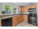 Well-lit kitchen featuring wood cabinetry, black appliances, and a double basin sink at 94 Sumner Nw Ave, Concord, NC 28027